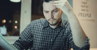 Un homme stressé et fatigué, tenant sa tête avec une main, illustrant les effets potentiels du manque de concentration ou de fatigue mentale.