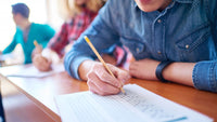 Illustration d'un étudiant concentré en train de remplir un test ou un questionnaire, évoquant la préparation mentale et la concentration avant les examens.